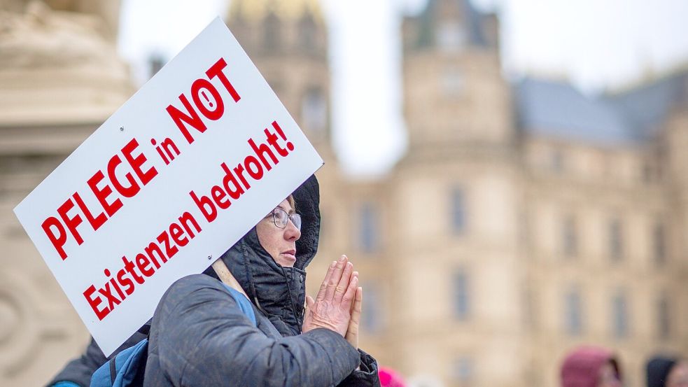 Bei einer Protestaktion vor dem Schweriner Landtag hält eine Teilnehmerin ein Schild mit der Aufschrift „Pflege in Not - Existenzen bedroht!“. Foto: Jens Büttner/dpa