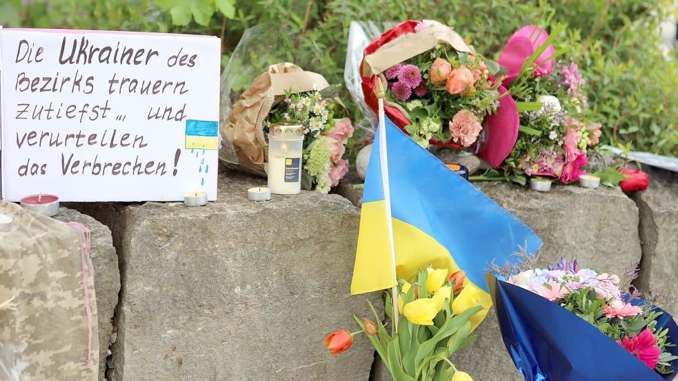 Am Gelände eines Einkaufszentrums, an dem zwei Männer aus der Ukraine getötet worden sind, wurden Blumen niedergelegt sowie eine kleine ukrainische Flagge aufgestellt. Foto: Constanze Wilz/dpa