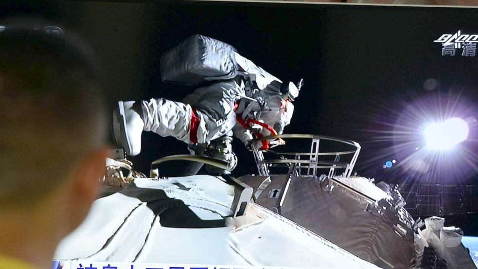 Ein Mann verfolgt vor dem Fernseher die Live-Übertragung eines Außeneinsatzes an der Raumstation „Tiangong“ (Archivbild). Foto: Sheldon cooper/SOPA Images via ZUMA Wire/dpa