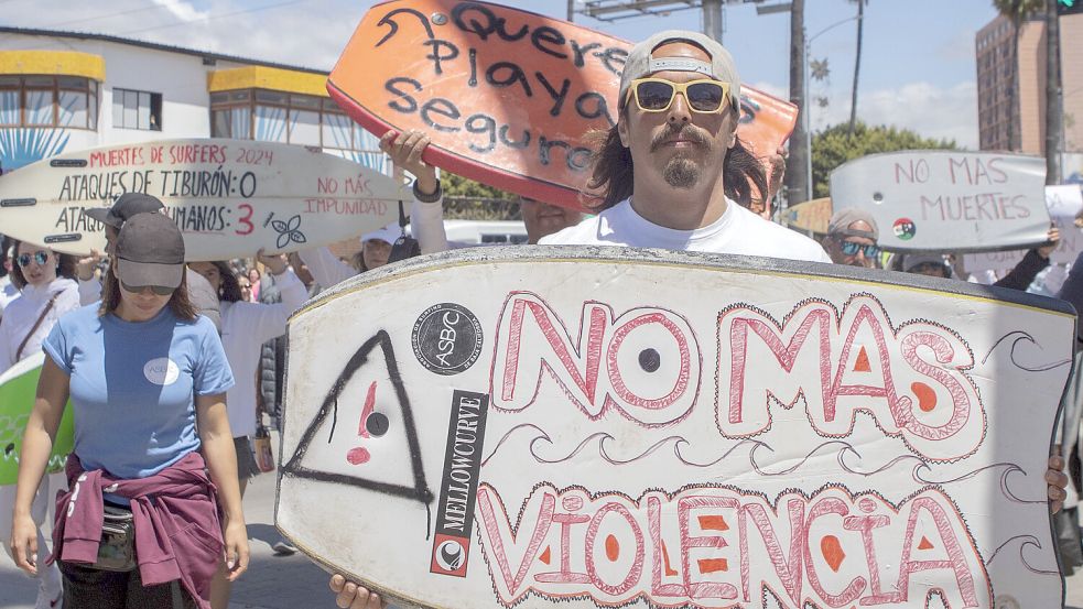 Ein Mann hält ein Bodyboard mit der spanischen Aufschrift „Keine Gewalt mehr“ und protestiert damit gegen das Verschwinden von ausländischen Surfern. Foto: dpa/AP/Karen Castaneda