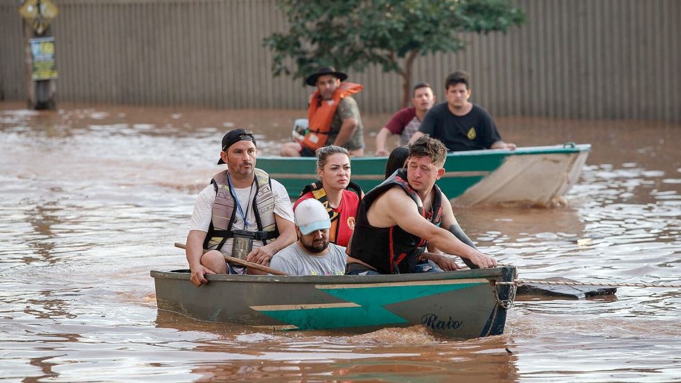 Mitglieder eines Rettungsteams bei der Evakuierung von Menschen, die von einer Überschwemmung betroffen sind. Foto: Claudia Martini/XinHua/dpa