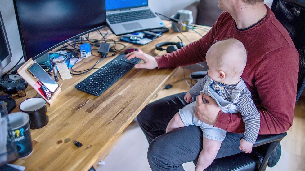 Ein junger Vater im Home-Office mit seinem sechs Monate alten Sohn. Foto: Jens Büttner/dpa