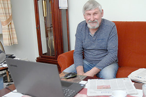 Rudolf Onnen mit einer Tasse Kaffee und der OZ vor dem Laptop. Rechts neben ihm liegt der Ordner, in dem er seine Leserbriefe archiviert. Bild: Ellinger