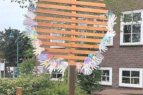 Bunte Hände zieren das Maibaum-Schild bei der Grundschule Bunde. Bild: Grundschule