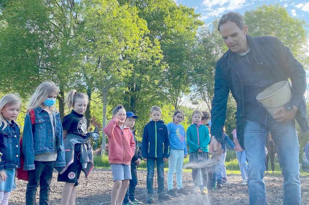 Hinrich Sparringa zeigt den Kindern, was sie bei der Aussaat beachten müssen.