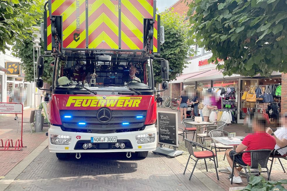 Werbeschilder ragen in die Fußgängerzone, an den Tischen sitzen Menschen und beobachten die Szenerie: Die Norder Feuerwehr hatte am Montag große Probleme, zum Einsatzort zu kommen. Foto: Feuerwehr Norden
