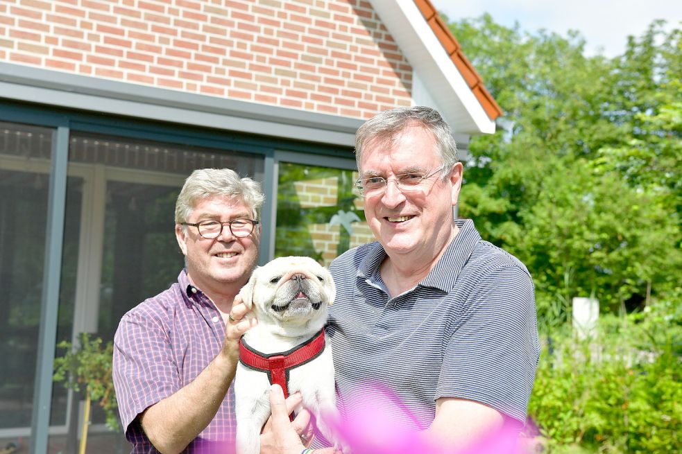 Alexander (links) und Ulrich Baer wohnen jetzt mit ihrem Mops „Puh“ in Loquard. Sie sind ein Beispiel für viele Menschen aus Nordrhein-Westfalen, die es nach Ostfriesland gezogen hat. Foto: Wagenaar