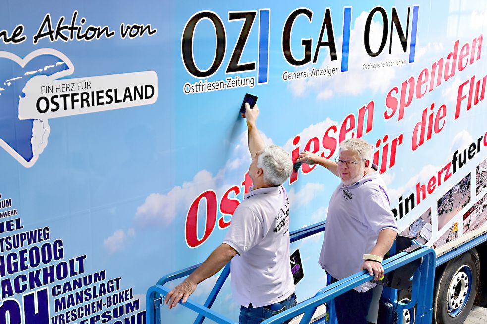 Rollende Werbung für die Spendenaktion zugunsten der Flutopfer in Eschweiler und Stolberg: Salman Ali (links) und Thorsten Boelen von der Firma Boelen Werbetechnik bekleben den Laster der Spedition Merkel aus Moormerland. Foto: Stromann