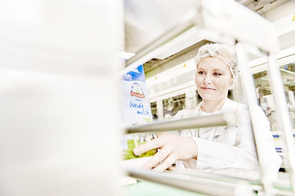 Eine Mitarbeiterin der Ammerland Molkerei hantiert in der Produktionsstätte mit einer Milchpackung. Bild: Ammerland
