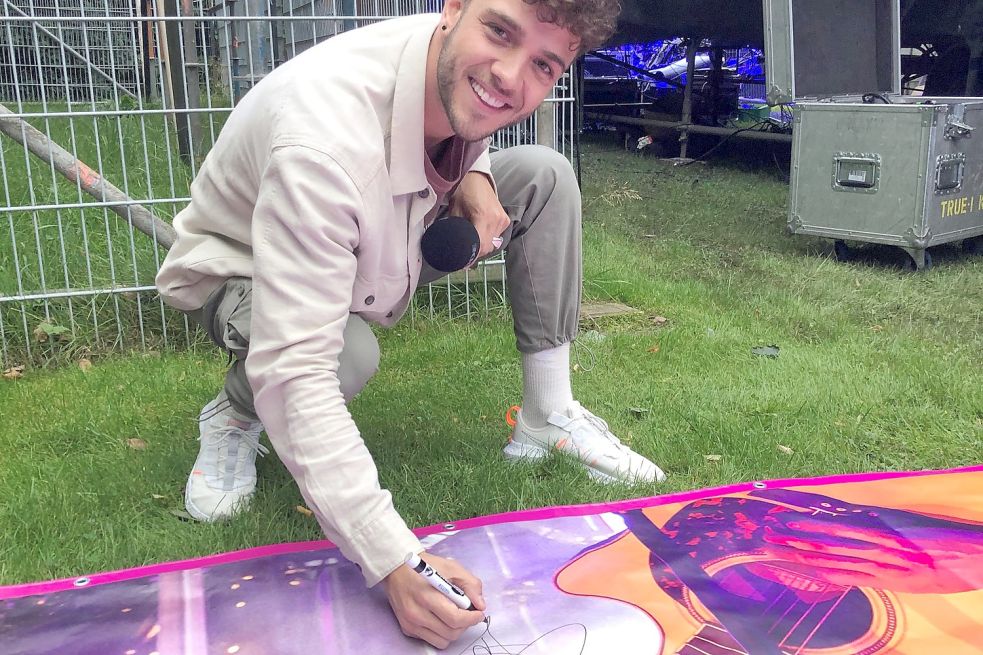 Für seine ostfriesischen Fans unterzeichnet Luca Hänni ein Werbe-Banner von seinem Auftritt in Emden. Nun wird es auf Instagram verlost. Fotos: Fäustel