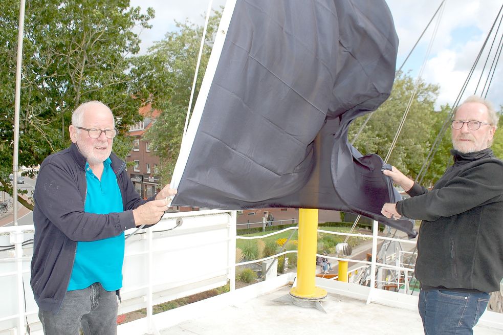 Zeichen des Protestes: Vereinschef Heinz-Günther Buß (links) und Crewmitglied Wolfgang Janßen hissen eine schwarze Flagge auf dem Feuerschiff. Foto: H. Müller