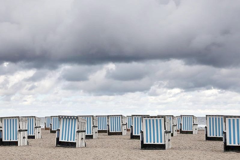 Dunkle Wolken ziehen über den Ostseestrand von Warnemünde. Sommerliches Wetter ist vorerst nicht in Sicht. Foto: Bernd Wüstneck/dpa-Zentralbild/dpa