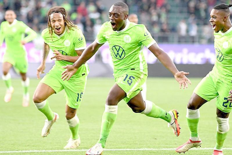 Wolfsburgs Jerome Roussillon (M) jubelt nach seinem Treffer zum 1:0 mit seinen Teamkollegen Kevin Mbabu (l) und Ridle Baku (r). Foto: Swen Pförtner/dpa