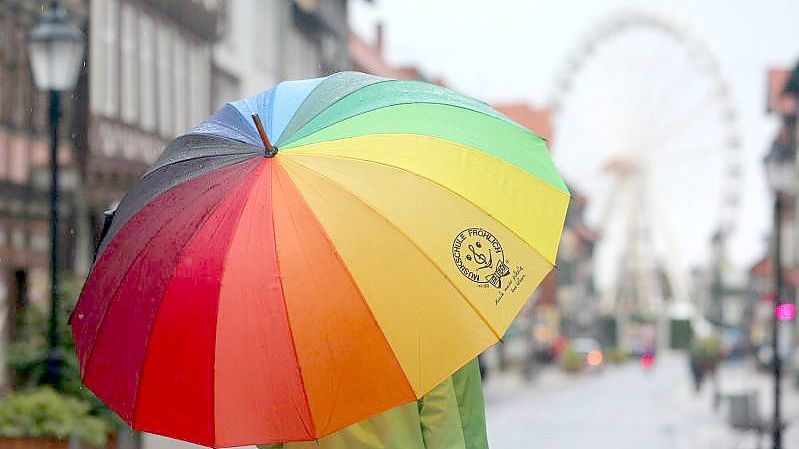 Passanten gehen bei Regenwetter durch die Fußgängerzone von Wernigerode in Sachsen-Anhalt. Foto: Matthias Bein/dpa-Zentralbild/dpa