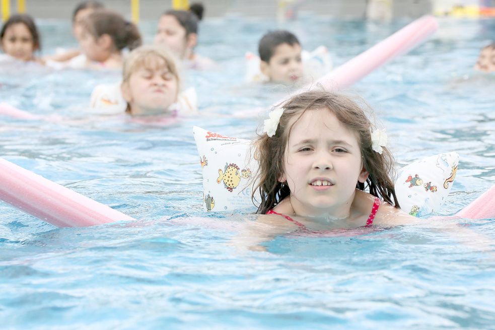 Immer schön den Kopf nach oben, nur keinen Kontakt zum Wasser. Den Kindern, die auf diesem Symbolbild schwimmen lernen sollen, ist der Widerwillen dem Element gegenüber deutlich anzumerken. Foto: Pilick/dpa