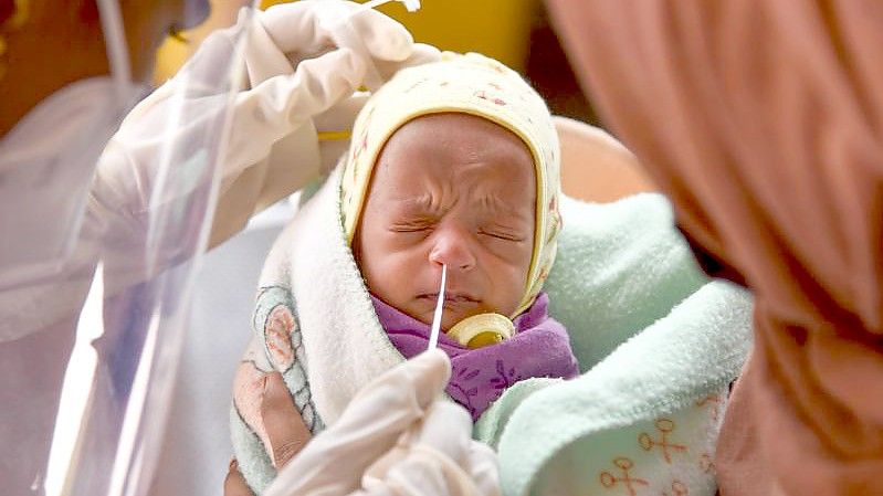 Eine Medizinerin entnimmt einem Baby in einem Krankenhaus einen Nasenabstrich für einen Corona-Test. Foto: Farooq Sayed/PTI/dpa