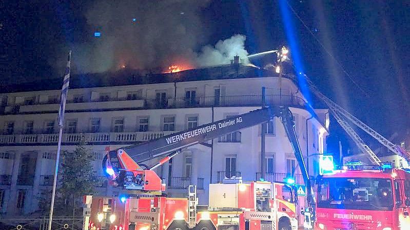 Die Feuerwehr löscht von Drehleitern aus das Hotel „Badischer Hof“. Etwa 160 Gäste mussten vor dem Feuer in Sicherheit gebracht werden. Foto: Patrick Neumann/SWR/dpa