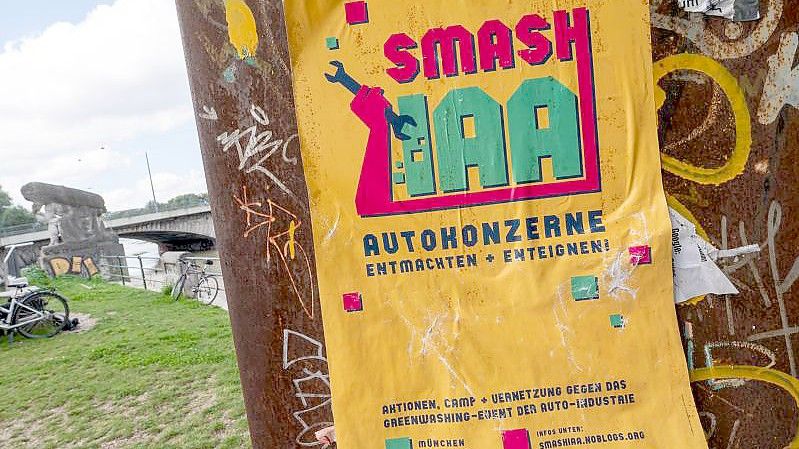 Ein gelbes Plakat mit der Aufschrift „Smash IAA Autokonzerne entmachten und enteignen!“ klebt an einer Wand in der Stadt. Foto: Peter Kneffel/dpa