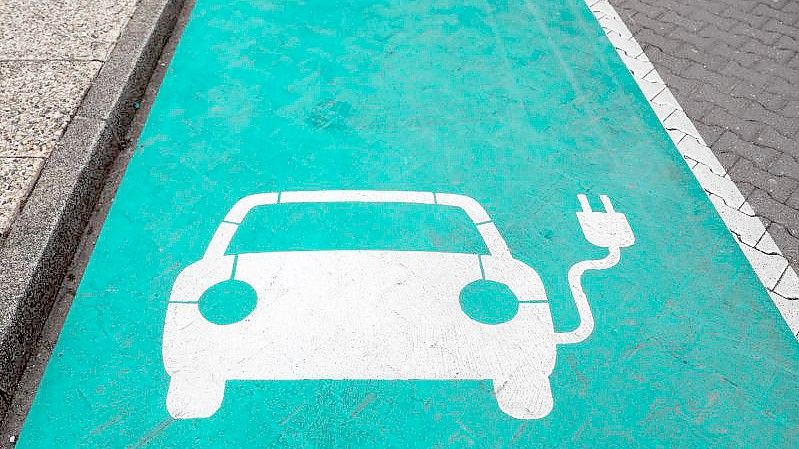 Ein stilisiertes Auto auf grünen Grund markiert einen Parkplatz mit Ladesäule für Elektrofahrzeuge. Foto: Jan Woitas/zb/dpa