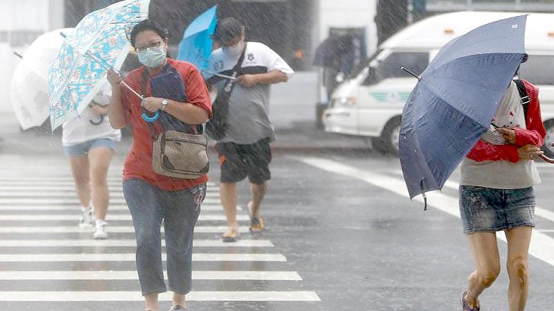 Menschen mit Regenschirmen kämpfen in Keelung gegen das Unwetter. Foto: Daniel Ceng Shou-Yi/ZUMA/dpa