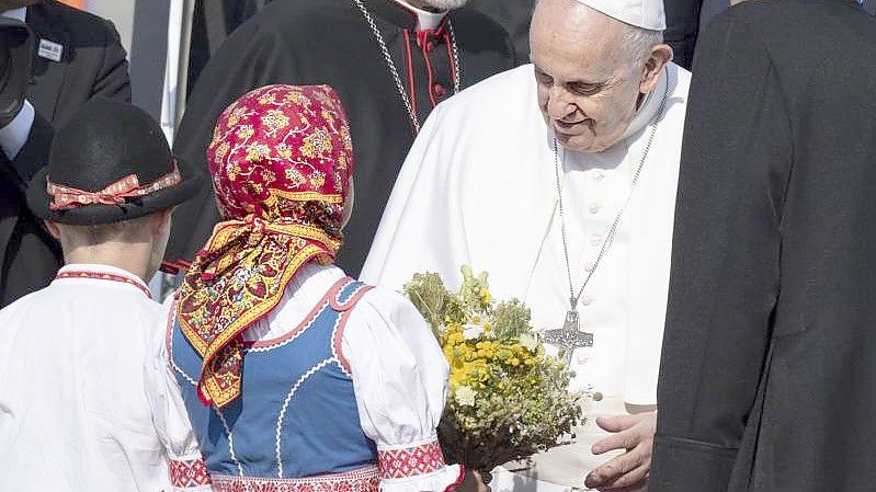Papst Franziskus wird von zwei Kindern in traditioneller Kleidung am Flughafen im slowakischen Bratislava empfangen. Foto: Pavel Neubauer/TASR/dpa