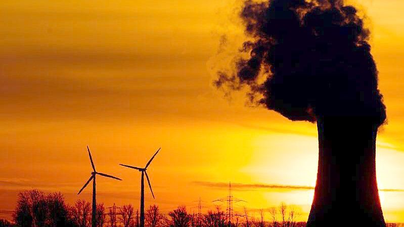 Zwei Windräder und ein Kohlekraftwerk im Licht der aufgehenden Sonne. Foto: picture alliance / dpa