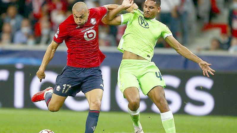 Maxence Lacroix vom VfL Wolfsburg (r) kann sich im Kampf um den Ball nicht gegen Burak Yilmaz vom OSC Lille durchsetzen. Foto: Michel Spingler/AP/dpa