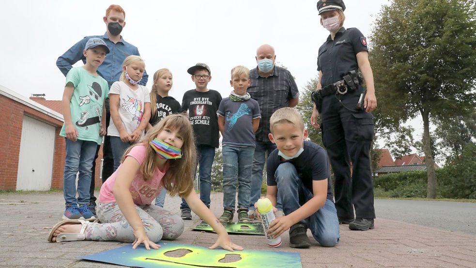 Lehrer André Janßen (hinten, von links), Wilhelm Doden vom Landkreis Aurich und Christiane Büchner von der Polizei Norden zusammen mit Zweitklässlern der Grundschule Jennelt: Der Schulweg der Kinder wird nun mit gelben Fußstapfen gekennzeichnet.
