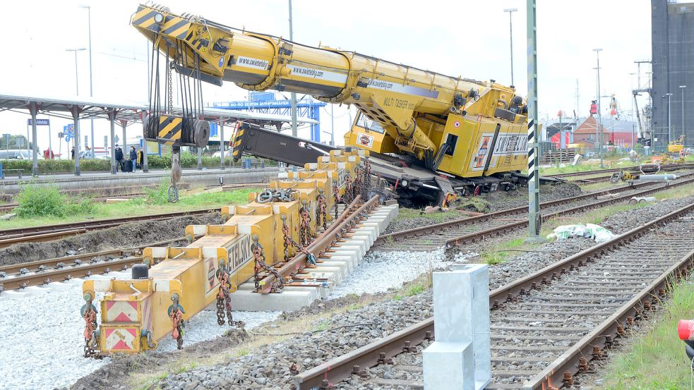 In Schieflage: Der eingesackte Schienenbaukran am Borkumanleger soll in der kommenden Woche geborgen werden. Der Ausleger des Fahrzeugs (vorne) sollte bereits am Freitag abtransportiert werden. Foto: F. Doden