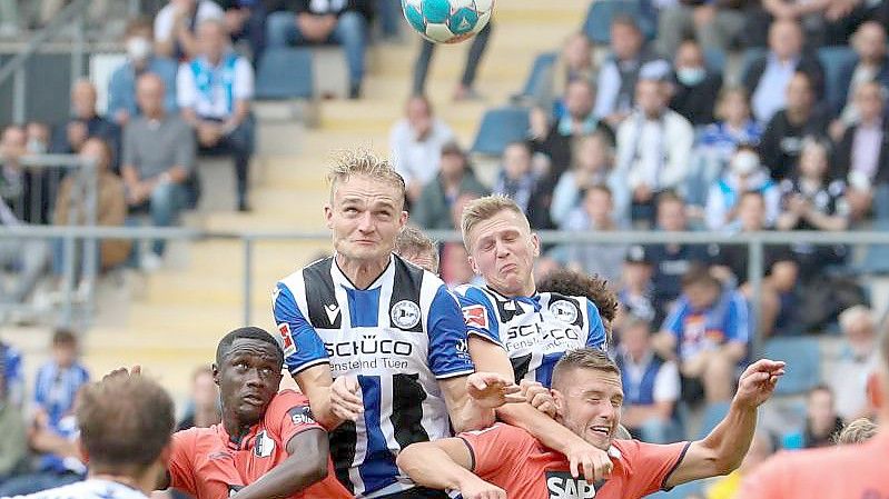 Bielefelds Amos Pieper (oben, l) setzt sich im Kopfballduell gegen Hoffenheims Diadie Samassekou (unten, l-r) und Pavel Kaderabek durch. Foto: Friso Gentsch/dpa