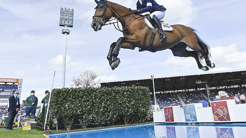 Springreiter Daniel Deußer überquert auf Killer Queen ein Wasserhindernis. Foto: Uwe Anspach/dpa