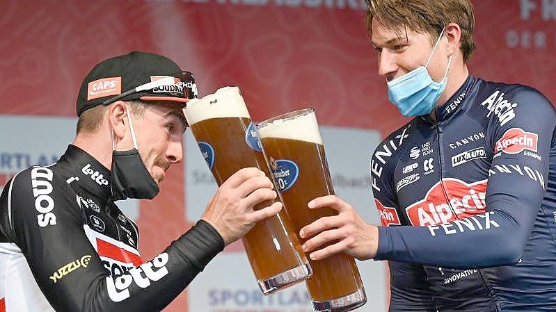 John Degenkolb (l) stößt mit Eschborn-Frankfurt-Sieger Jasper Philipsen an. Foto: Arne Dedert/dpa
