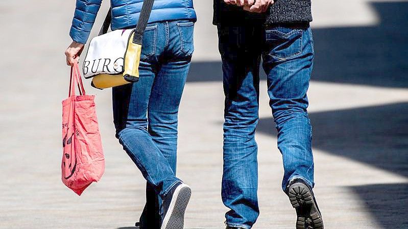Ein Paar mit einer Einkaufstasche beim Einkaufsbummel. Foto: Hauke-Christian Dittrich/dpa;