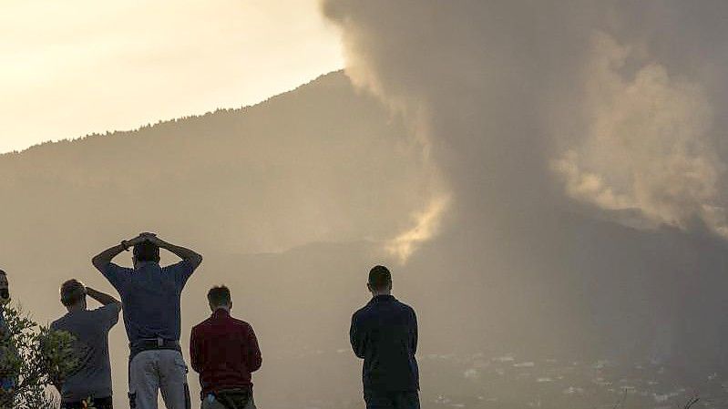 Anwohner blicken von einem Hügel aus auf die Lava, die weiterhin aus dem Vulkan auf der Insel La Palma fließt. Foto: Emilio Morenatti/AP/dpa