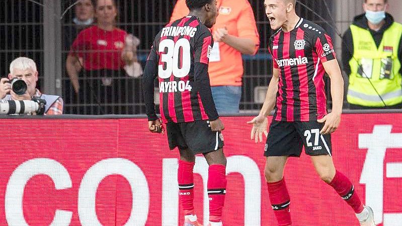 Leverkusens Jeremie Frimpong (l) und Torschütze Florian Wirtz jubeln nach dem Treffer zum 1:0. Foto: Marius Becker/dpa
