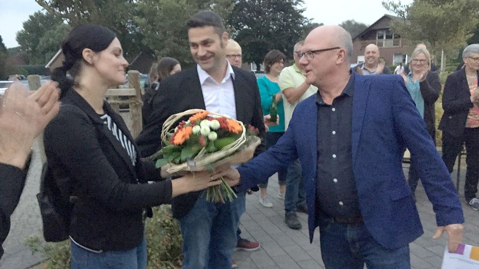 Für die Frau des Siegers, Sabine Busboom, gab es Blumen. Christoph Busboom (Mitte) bekam von dem noch amtierenden Samtgemeindebürgermeister Johann Boelsen den symbolischen Rathausschlüssel. Foto: Kraft