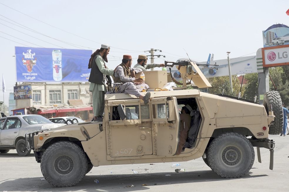 Taliban-Kämpfer stehen vor dem internationalen Flughafen Hamid Karzai Wache. Tausende von Menschen drängten sich am Montag auf dem Flughafen der afghanischen Hauptstadt, im verzweifelten Versuch, aus dem Land zu fliehen, nachdem die Taliban die vom Westen unterstützte Regierung gestürzt hatten. Foto: -/AP/dpa