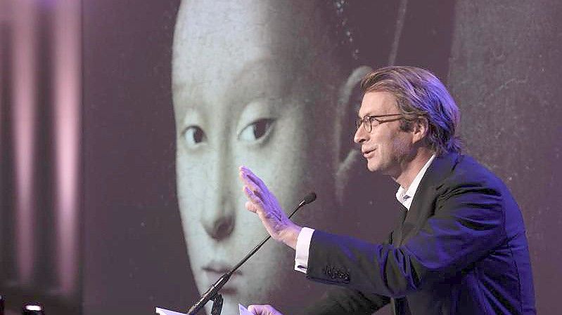 Taco Dibbits, Generaldirektor des Rijksmuseums, spricht über die Ausstellung "Remember Me" (dt: Vergiss mich nicht), während das Porträt einer jungen Frau von Petrus Christus auf die Leinwand projiziert wird. Foto: Peter Dejong/AP/dpa