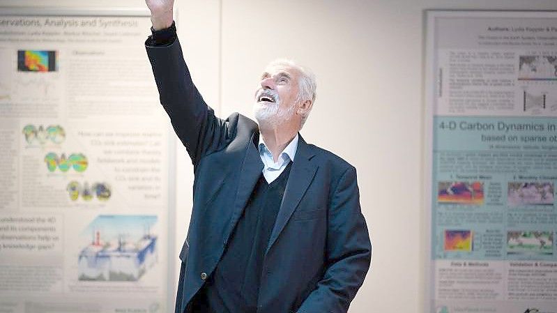 Klaus Hasselmann winkt im Max-Planck-Institut für Meteorologie in Hamburg jubelnden Mitarbeitenden zu. Foto: Daniel Reinhardt/dpa