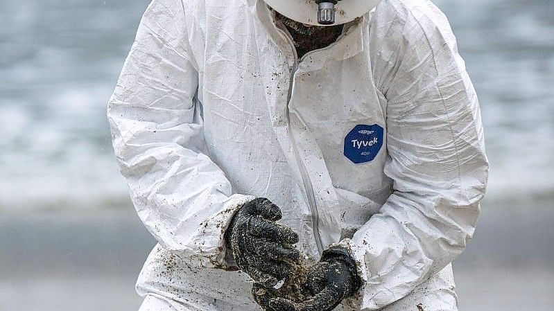 Ein Arbeiter in einem Schutzanzug säubert einen Strandabschnitt. Foto: Jason Ryan/ZUMA Press Wire Service/dpa