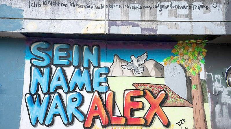 Auf einer Mauer entlang ein Graffiti "Sein Name war Alex" für den getöteten Tankstellen-Mitarbeiter gemalt. Foto: Oliver Dietze/dpa