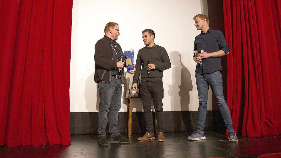 Michael Kreihsl (links) bekommt den „Schreibtisch am Meer“ überreicht von Festival Manager Lucian Hoch und Filmfest-Moderator Ansgar Ahlers. Foto: Filmfest