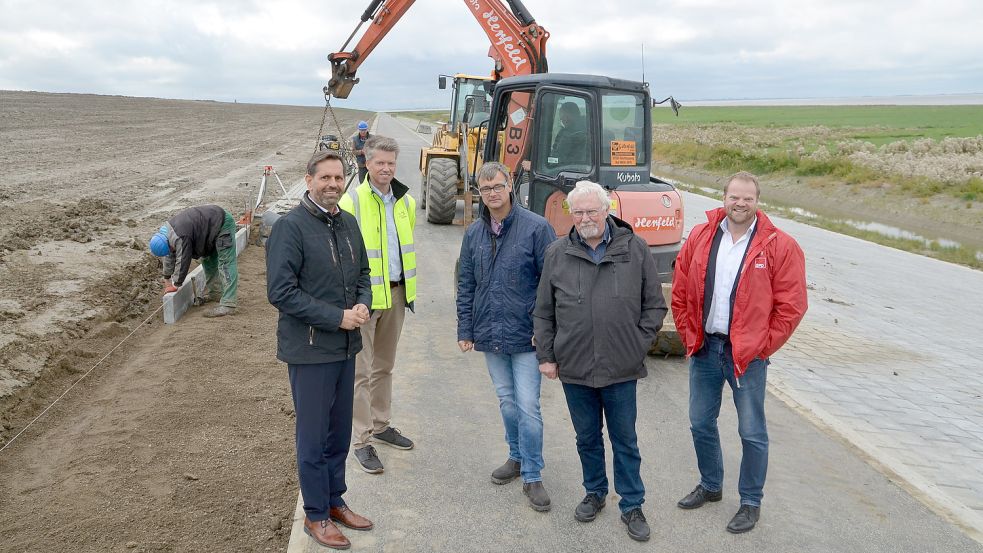 Olaf Lies (im Vordergrund, von links), Dr. Thomas Schoneboom vom NLWKN, Gerd-Udo Heikens (Deichacht), Alwin Brinkmann und der SPD-Landtagsabgeordnete Matthias Arends stellten sich an der Baustelle für ein Foto auf. Im Hintergrund sind Mitarbeiter der Firmen G. Herfeld aus Rechtsupweg und Jeschke aus Blomberg zu sehen. Fotos: Hillebrand