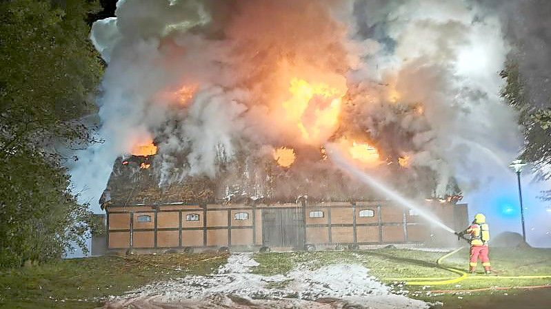 Feuerwehrleute löschen das Feuer in der mit Reet gedeckten Museumsscheune. Foto: -/TNN/dpa