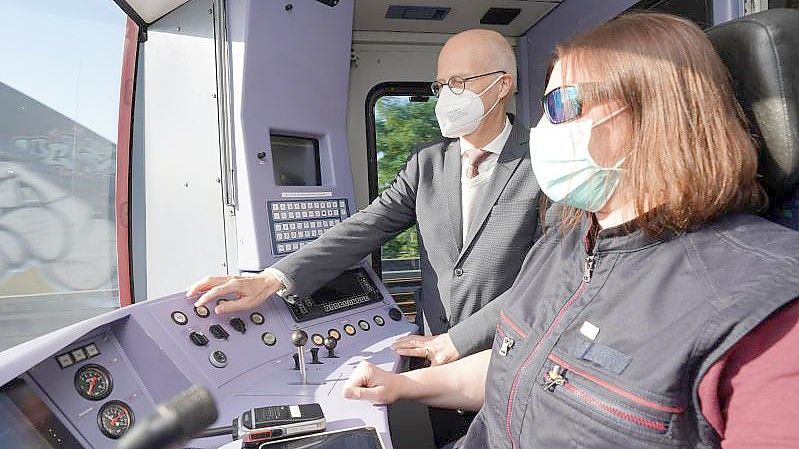 Hamburgs Erster Bürgermeister Peter Tschentscher schaltet neben Triebfahrzeugführerin Valeska Hoop per Knopfdruck in den vollautomatischen Modus. Foto: Marcus Brandt/dpa