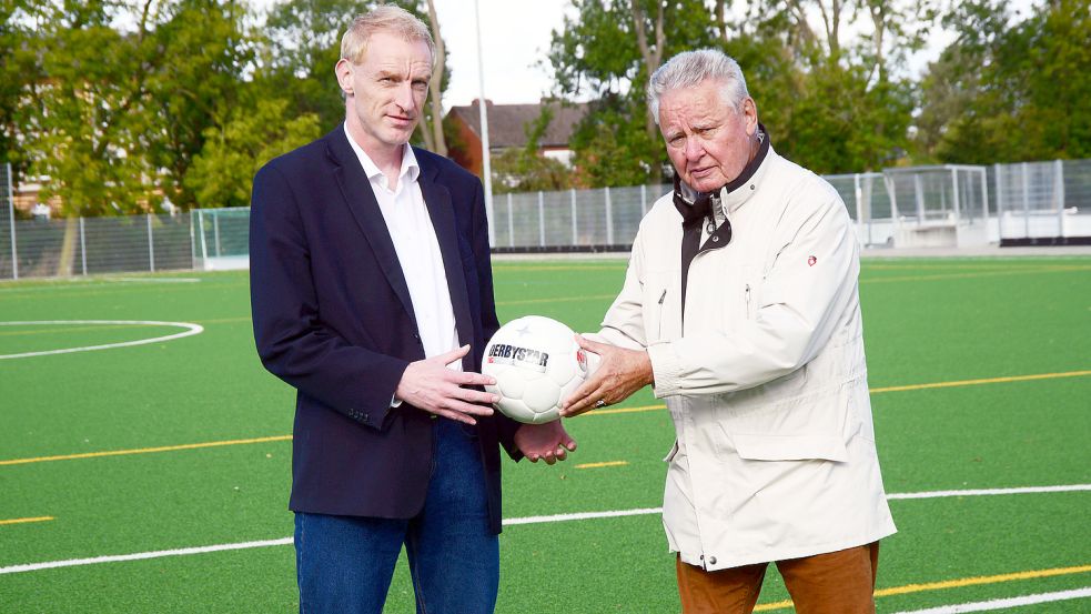 Sinnbildlich: Der scheidende Chef des Stadtsportbundes, Hans-Jürgen Wehmhörner (rechts) gibt den Ball auf dem Kunstrasenplatz von Eintracht Emden JFV an seinen potenziellen Nachfolger Peter Bartsch ab. Foto: F. Doden