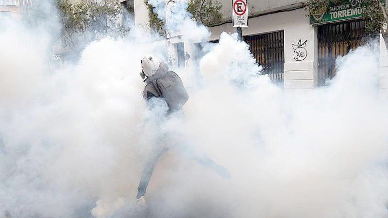 Ein Demonstrant wirft einen Tränengaskanister zurück, der von der Polizei abgefeuert wurde, um einen Protest in Santiago aufzulösen. Foto: Matias Basualdo/ZUMA Press Wire/dpa