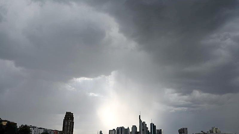 Dunkle Wolken ziehen über die Bankentürme und Hochhäuser während der Regen über der Bankenstadt einsetzt. (Archivbild). Foto: Arne Dedert/dpa