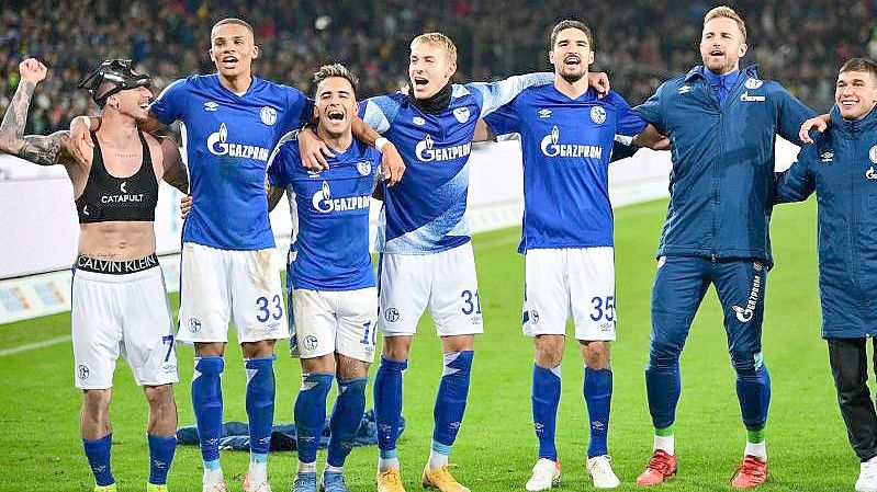 Schalkes Spieler feiern den Last-Minute-Sieg in Hannover vor ihren mitgereisten Fans. Foto: Julian Stratenschulte/dpa