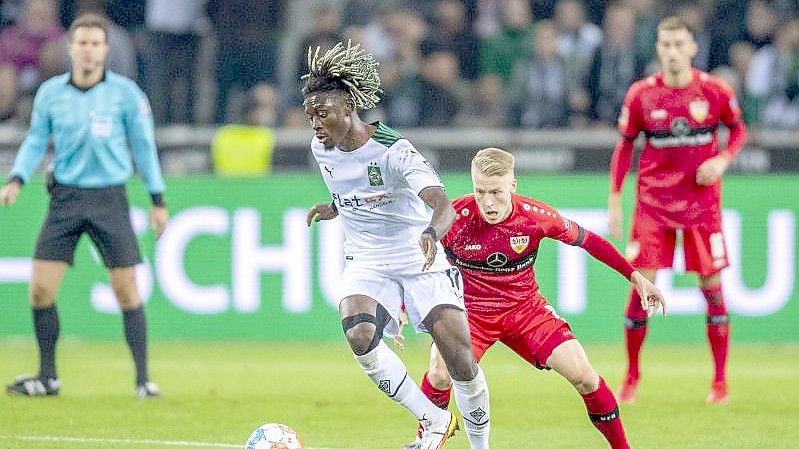 Gladbachs Kouadio Kone (l) und Stuttgarts Chris Führich kämpfen um den Ball. Foto: David Inderlied/dpa